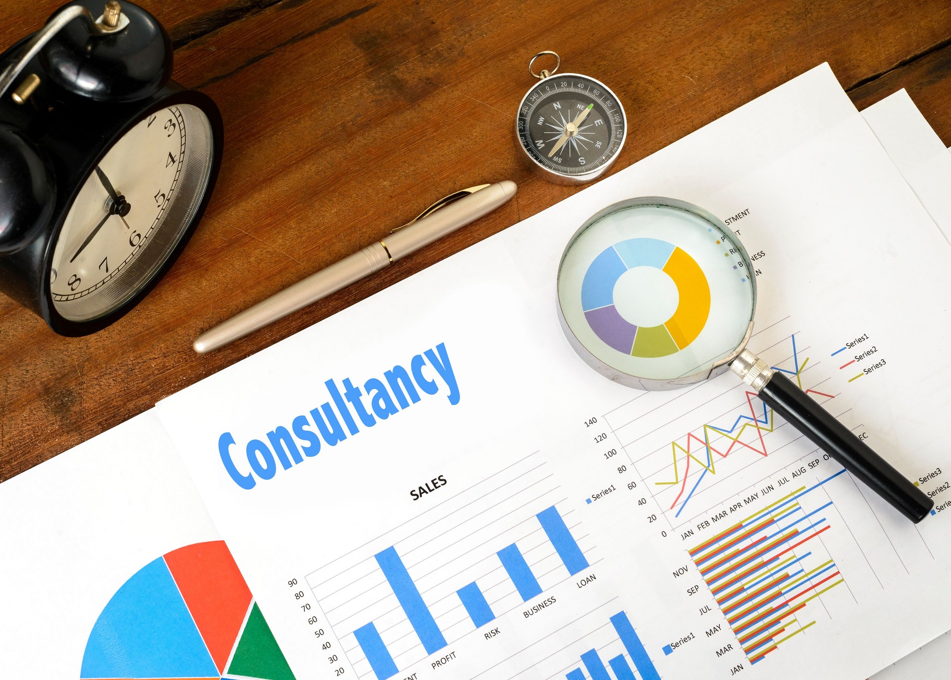 "Consultancy" text on paper sheet with magnifying glass on chart